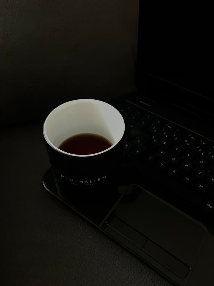 Simple black coffee cup beside a sleek laptop, embodying a minimalist workspace.