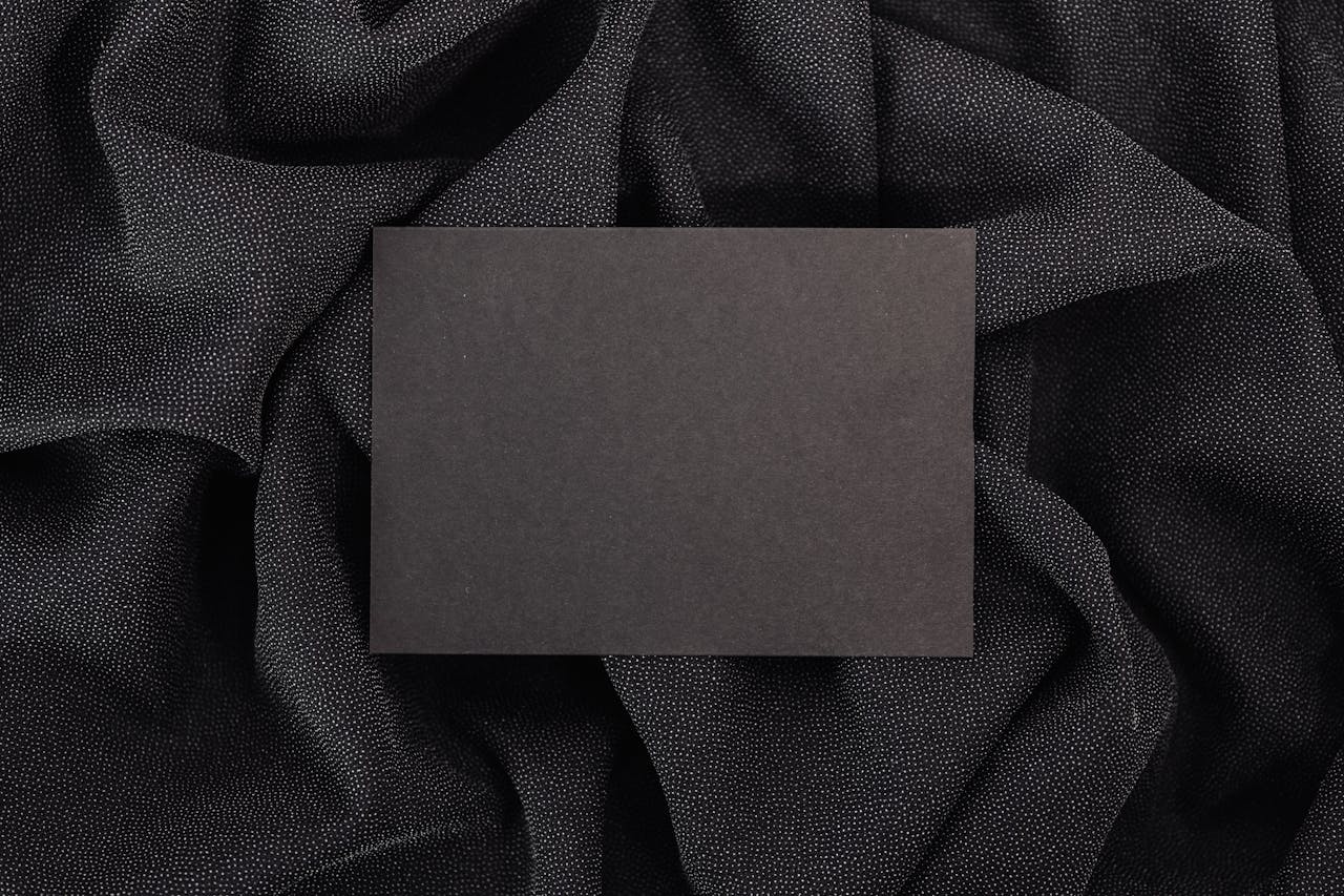 A black card placed on luxurious black textured fabric, perfect for mockups.